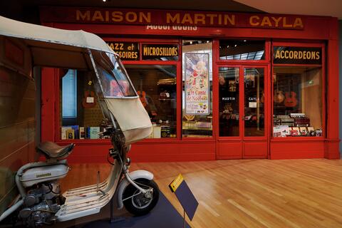 Triporteur Maugein devant la devanture de la Boutique Cayla