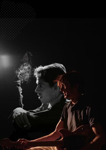 Le guitariste et chanteur Raphaël Moraine se tient de profil devant un portrait de Jacques Brel