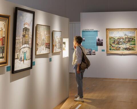 Une femme visitant une exposition de peintures de Charles Féola